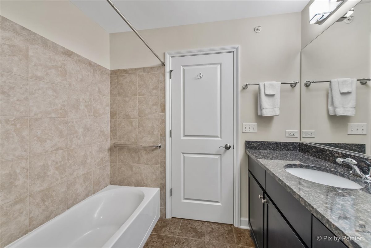 2122 Shermer Road Glenview, IL 60026 - Photo 27 of 37 a bathroom with a granite countertop sink a mirror and a bathtub