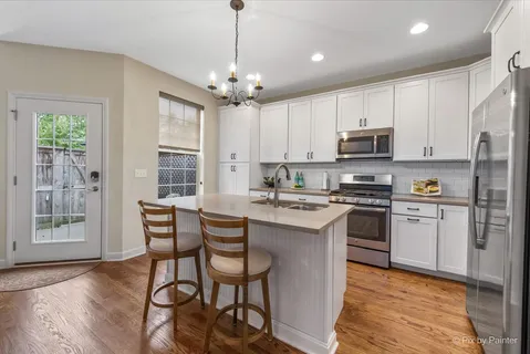 a kitchen with stainless steel appliances granite countertop a stove a sink dishwasher a refrigerator with a dining table and chairs