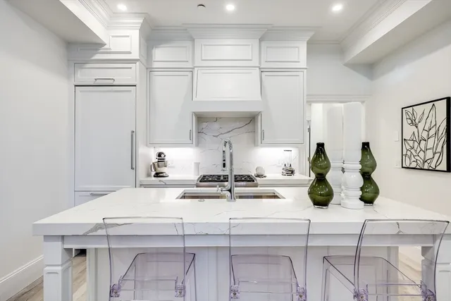 a view of a kitchen with kitchen island white cabinetry and chairs