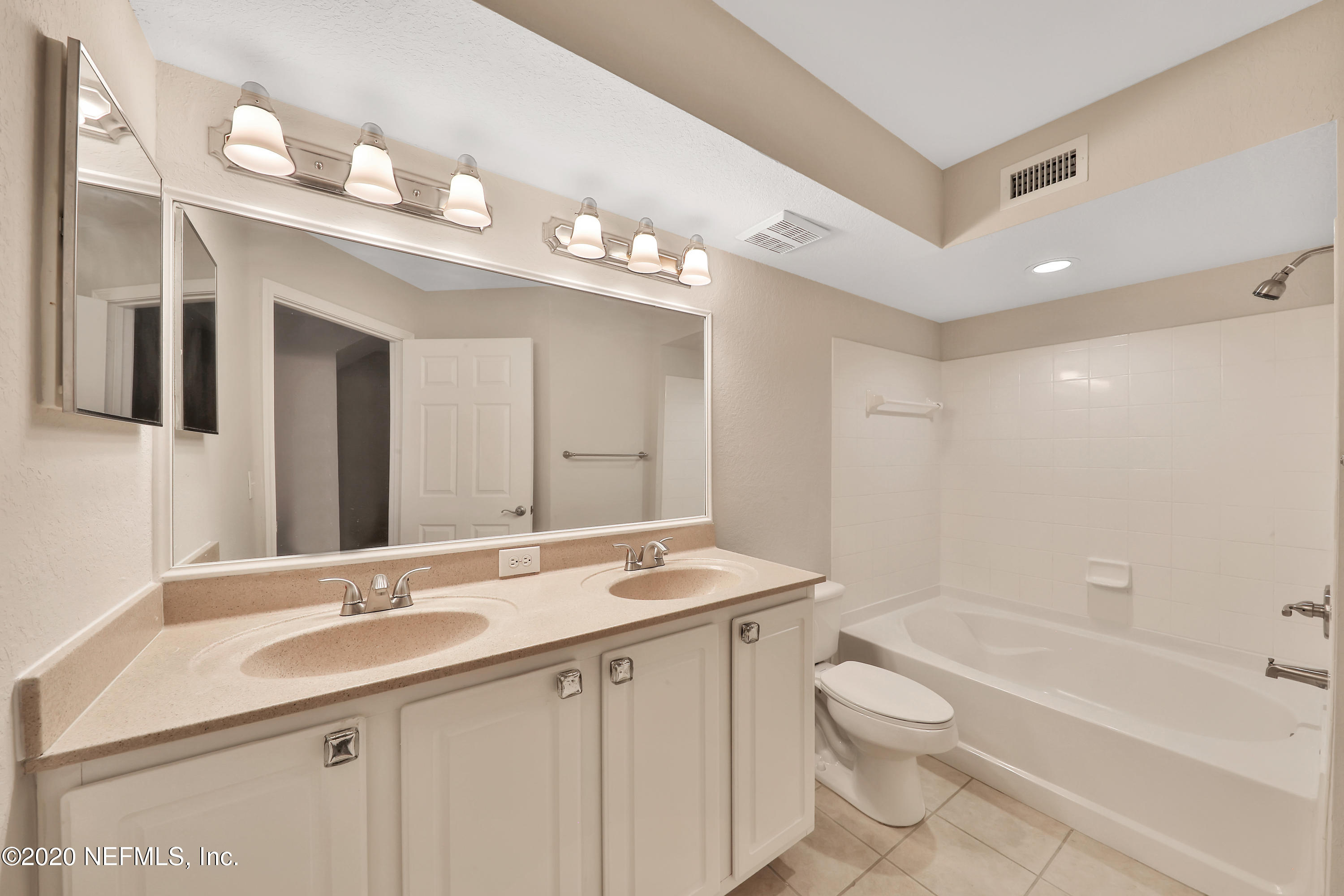 10075 Gate Parkway, Unit 1009 Jacksonville, FL 32246 - Photo 16 of 51 a bathroom with a granite countertop sink a toilet a large mirror a bathtub and shower