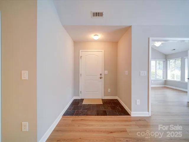 a view of a hallway with wooden floor and a bathroom