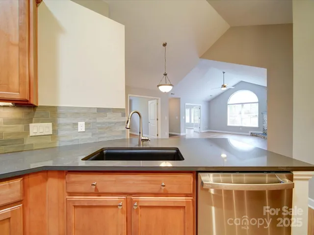 a view of a kitchen with a sink and dishwasher a stove top oven with wooden floor