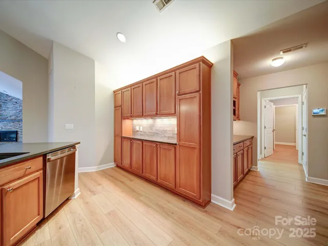 a view of hallway with wooden floor and cabinets
