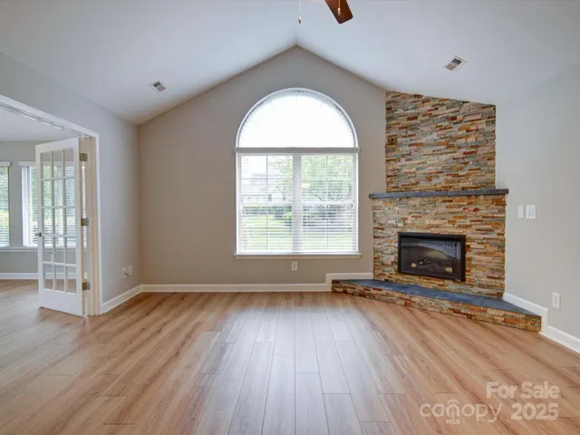an empty room with windows a fireplace and wooden floor
