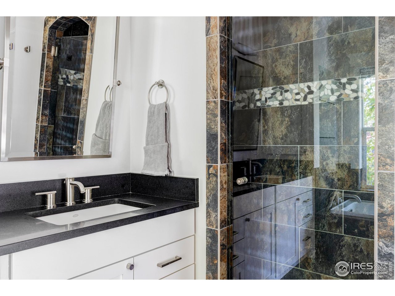 2129 23rd Street Boulder, CO 80302 - Photo 23 of 32 a bathroom with a granite countertop sink a mirror and shower