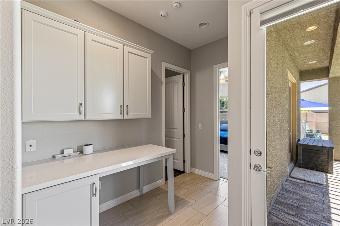7036 Arabian Ridge Street Las Vegas, NV 89131 - Photo 39 of 64 Hallway leading to bedrooms 4 and 5 with a functional built-in workspace with cabinetry for ideal storage and organization. Also easy access to the covered patio.