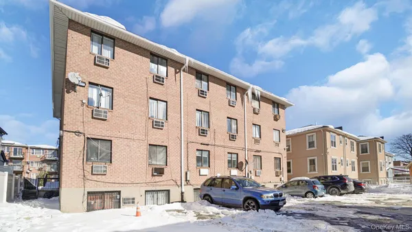 a front view of a building with lot of cars and trees