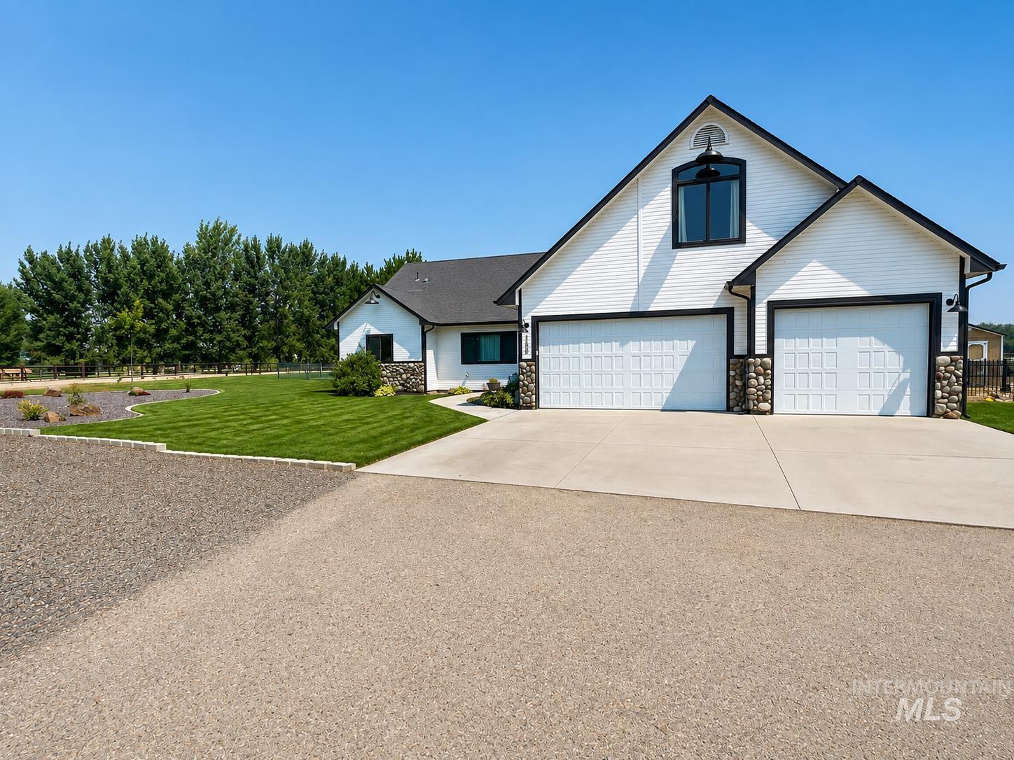 11650 Willis Road Middleton, ID 83644 - Photo 1 of 31 Expansive property featuring a detached metal-sided outbuilding with three garage doors, a main residence with an attached two-car garage, and a large open lot