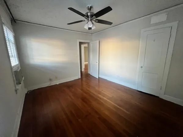 an empty room with wooden floor and a ceiling fan
