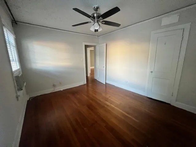 an empty room with wooden floor and a ceiling fan