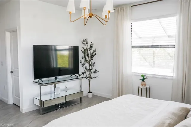 a bedroom with a bed and a flat tv screen on the dresser