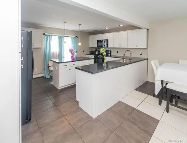 a kitchen with stainless steel appliances kitchen island granite countertop a refrigerator and a sink