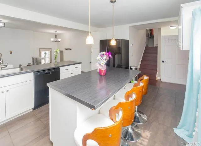 a kitchen with stainless steel appliances granite countertop a sink a refrigerator and a dining table