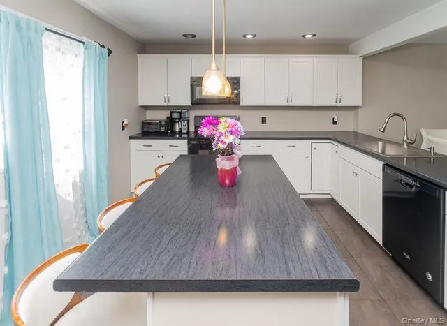 a kitchen with kitchen island white cabinets stainless steel appliances a sink and a window