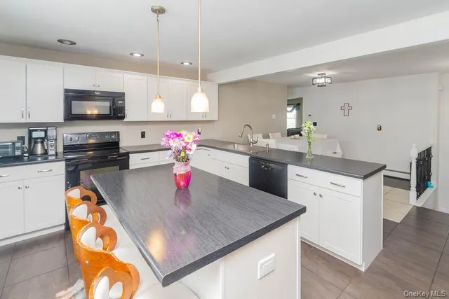 a kitchen with stainless steel appliances granite countertop a sink a stove top oven a chimney and cabinets