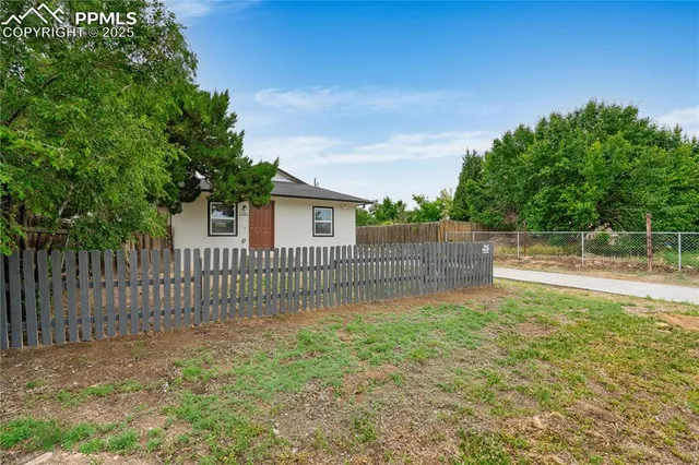 a view of a backyard with a small cabin and wooden fence