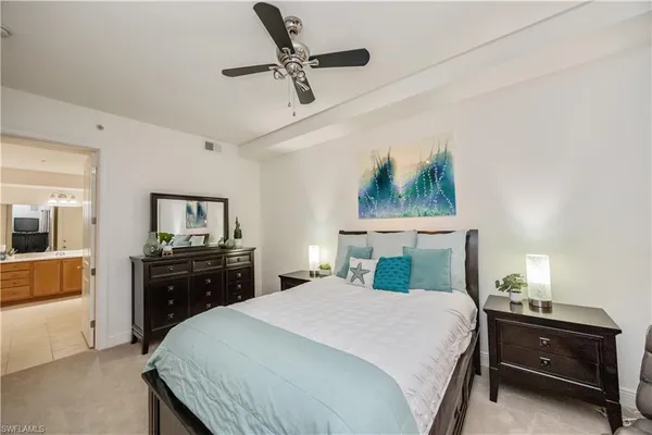 a spacious bedroom with a bed and a flat tv screen on dresser