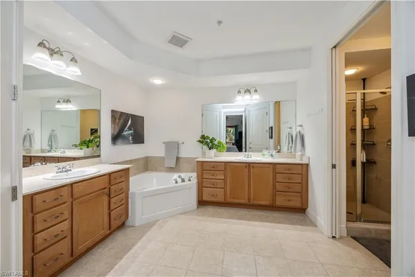 a spacious bathroom with a granite countertop sink a mirror a bathtub and shower