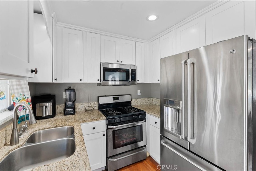 7167 Osbun Road San Bernardino, CA 92404 - Photo 24 of 35 a kitchen with refrigerator a stove and white cabinets
