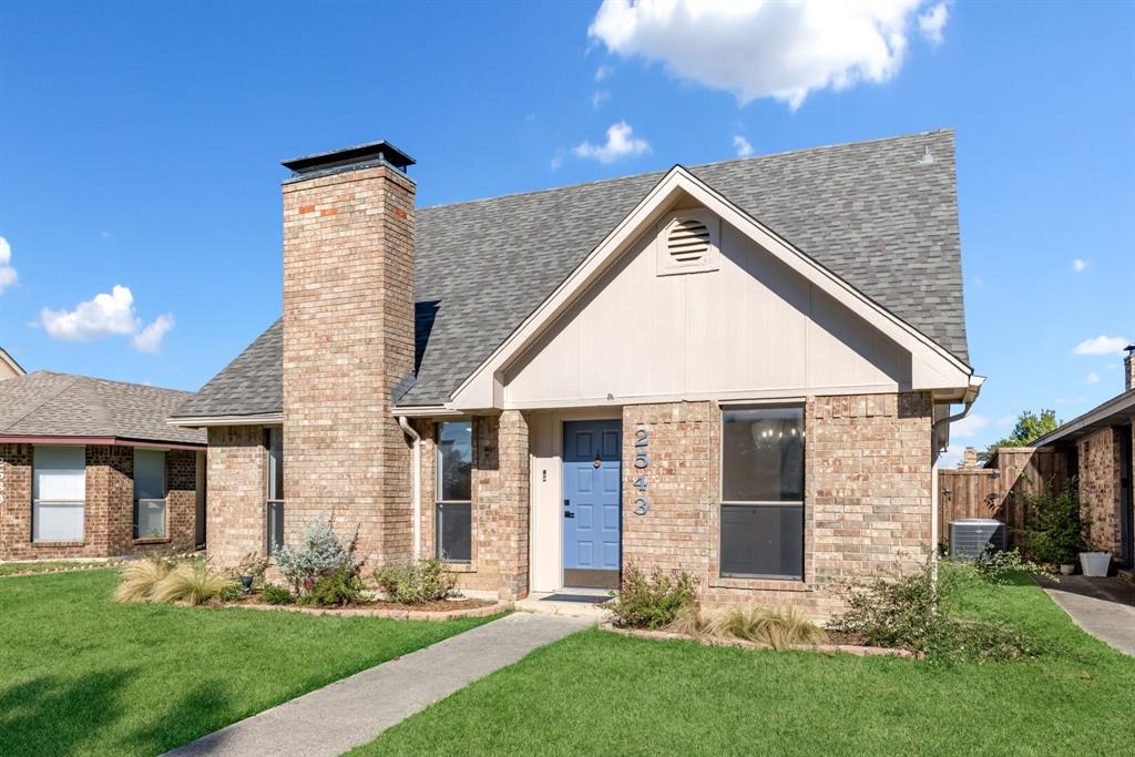 a view of a house with brick walls and a yard with plants