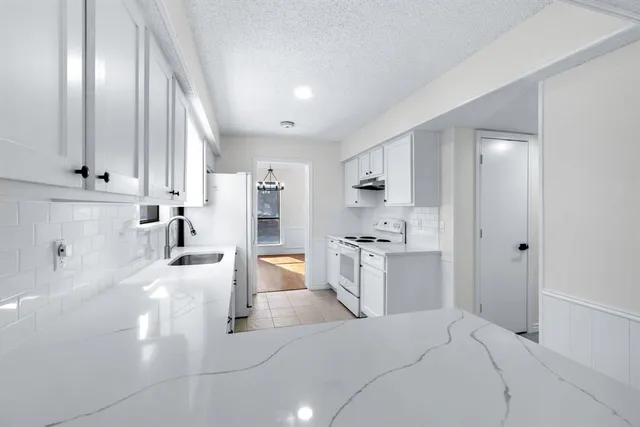a large white kitchen with kitchen island a sink stainless steel appliances and cabinets