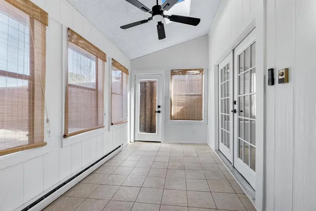 a view of a hallway to a livingroom with a chandelier fan and windows