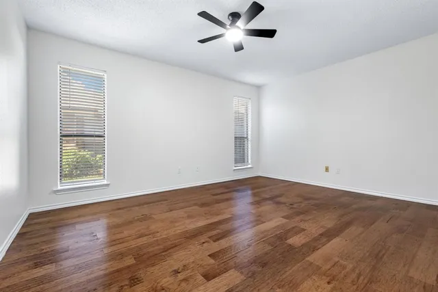 a view of empty room with wooden floor and fan