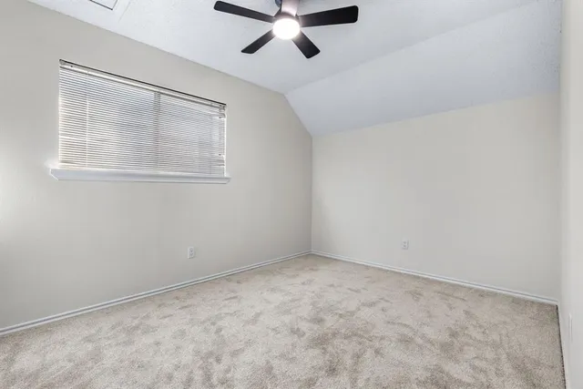 an empty room with ceiling fan and windows