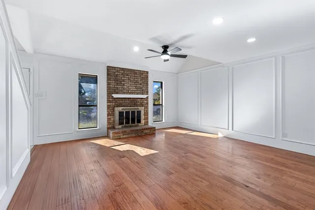 an empty room with wooden floor fireplace and fan