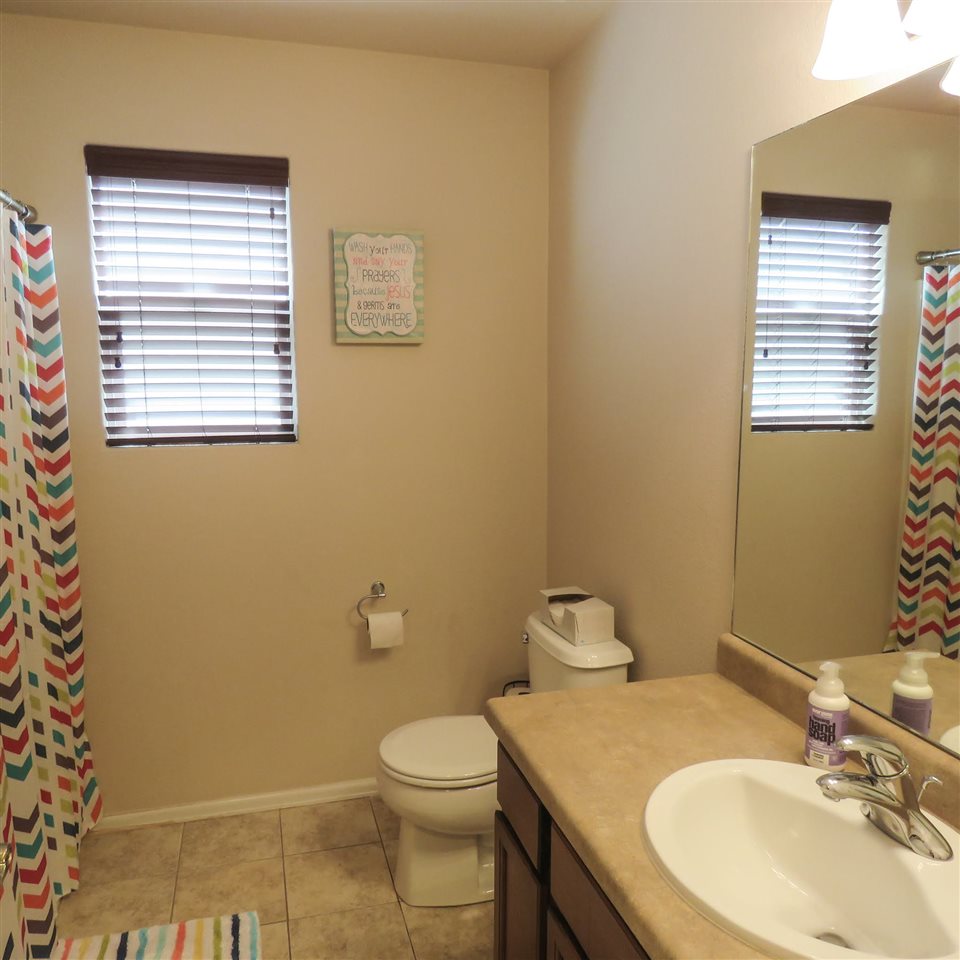 983 Kaley Street Fruita, CO 81521 - Photo 7 of 28 a bathroom with a granite countertop toilet a sink a mirror and a window