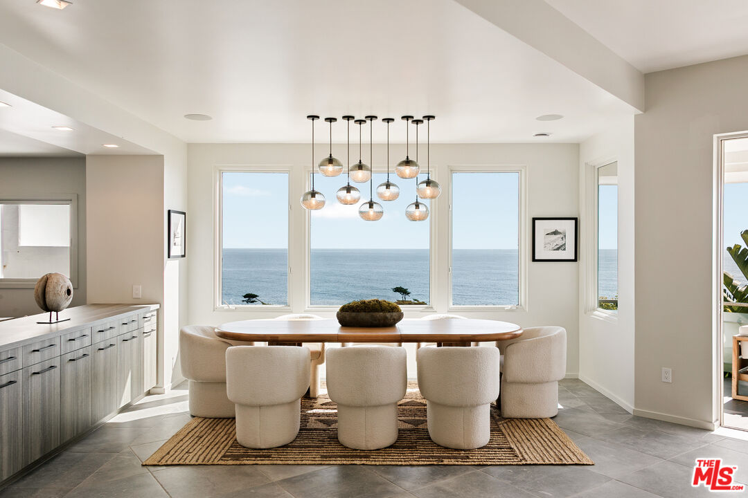 31558 Victoria Point Road Malibu, CA 90265 - Photo 16 of 55 a dining room with table chairs and white cabinets