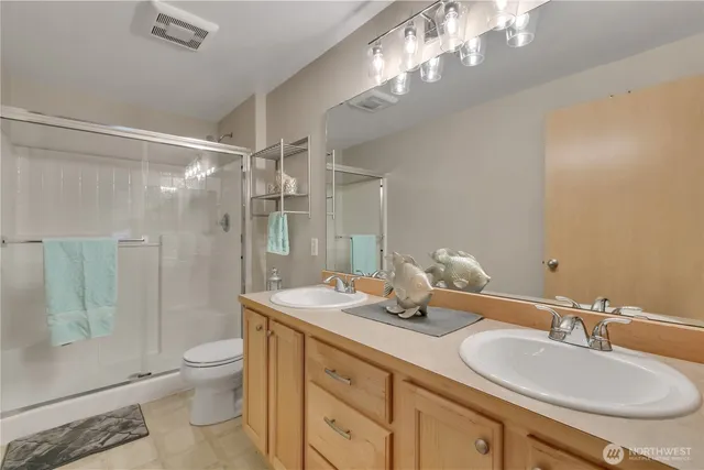 a bathroom with a double vanity sink toilet and shower