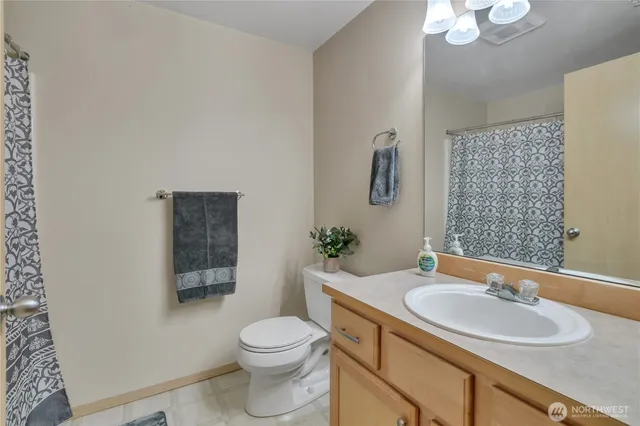 a bathroom with a toilet a sink a mirror a window and vanity