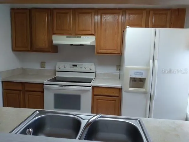 a kitchen with stainless steel appliances granite countertop a refrigerator and a stove top oven