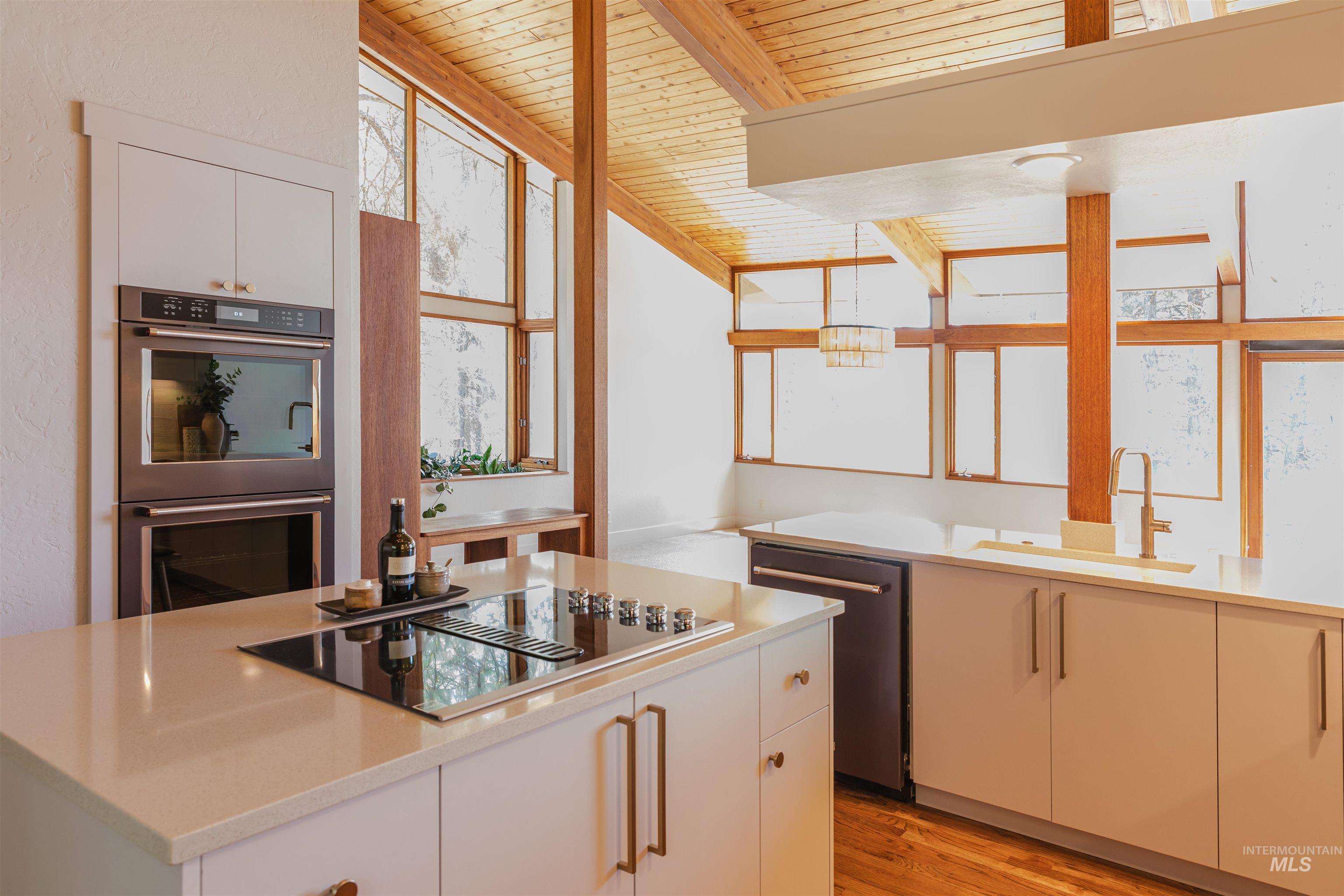 136 Silver Fox Trail McCall, ID 83638 - Photo 5 of 31 Kitchen featuring a central island with an integrated cooktop, double wall ovens, wood-finish flooring, and exposed wood beams