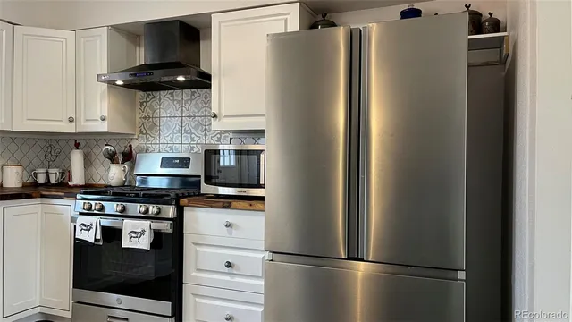 a kitchen with stainless steel appliances granite countertop a refrigerator and a stove