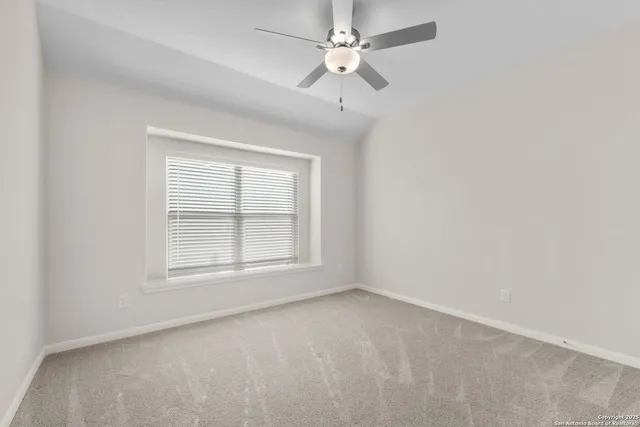 an empty room with a window and ceiling fan
