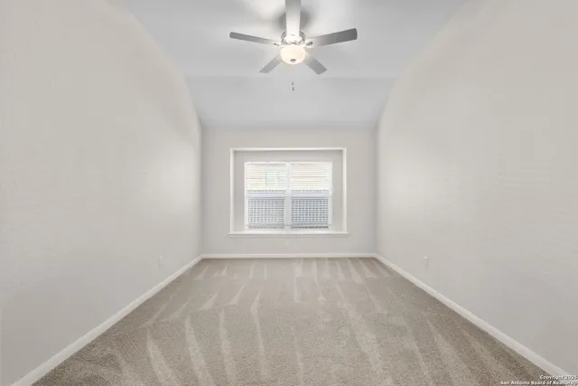 an empty room with a window and a fan
