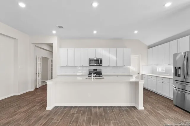 a view of kitchen with cabinets stainless steel appliances and wooden floor