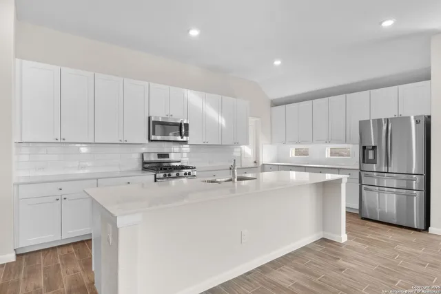 a kitchen with kitchen island a white cabinets and refrigerator