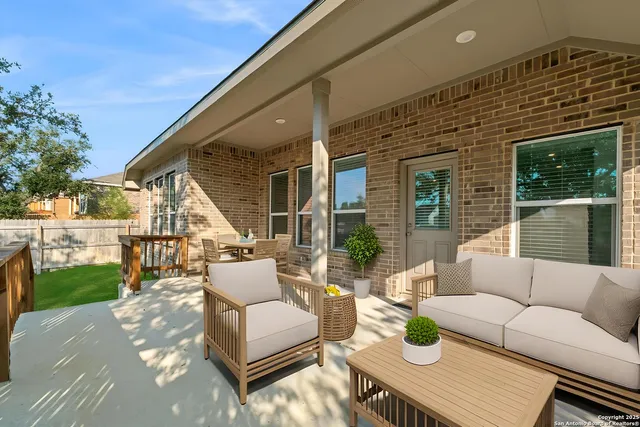 a view of a patio with couches table and chairs with wooden fence and plants