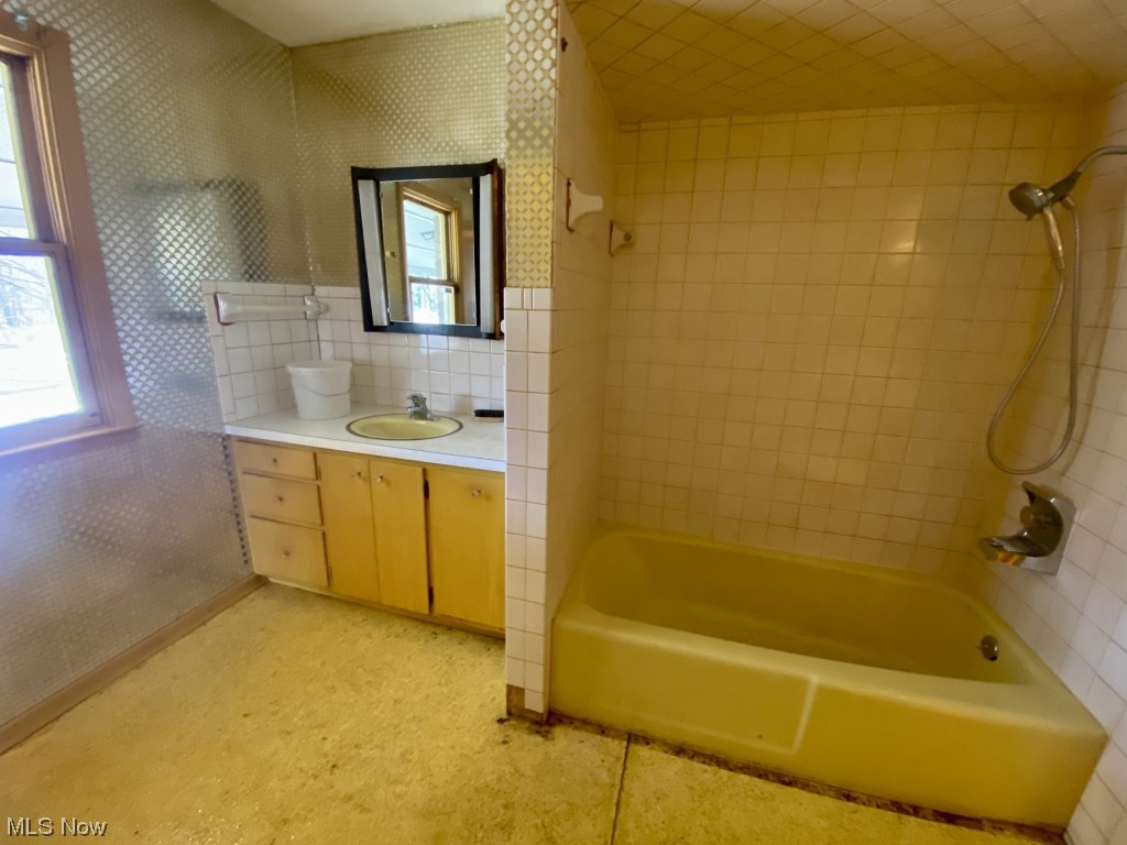 9520 Stone Road Litchfield, OH 44253 - Photo 13 of 22 Bathroom with large vanity, tile walls, tiled shower / bath combo, and backsplash