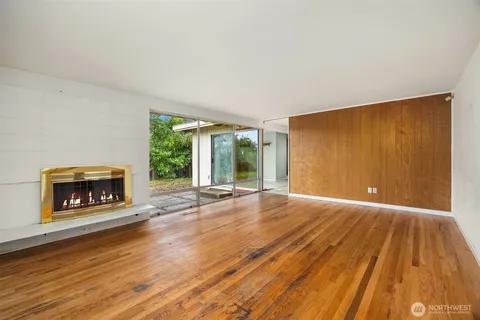 an empty room with wooden floor fireplace and windows