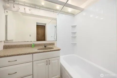 a bathroom with a granite countertop sink mirror and a bathtub