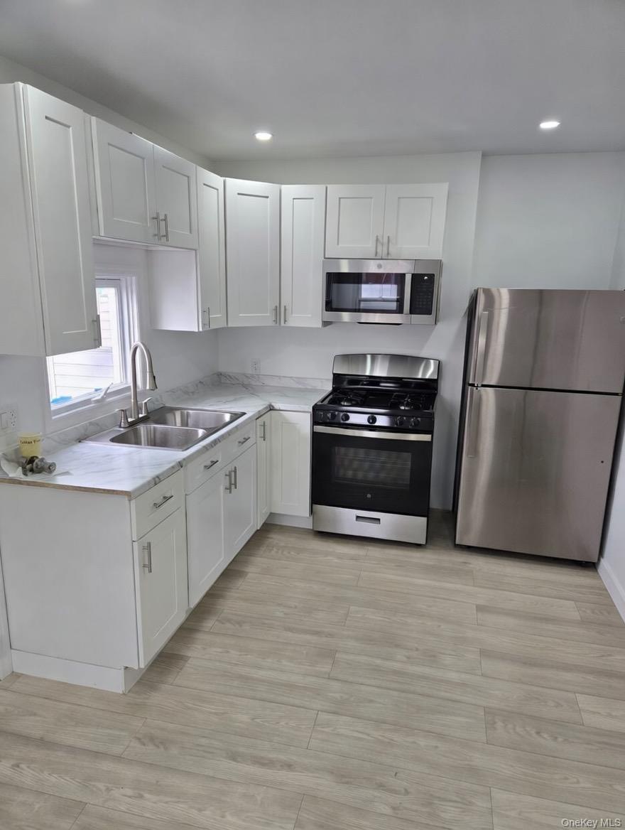 267 Morris Avenue Inwood, NY 11096 - Photo 7 of 10 a kitchen with stainless steel appliances a stove a sink a refrigerator a microwave and cabinets