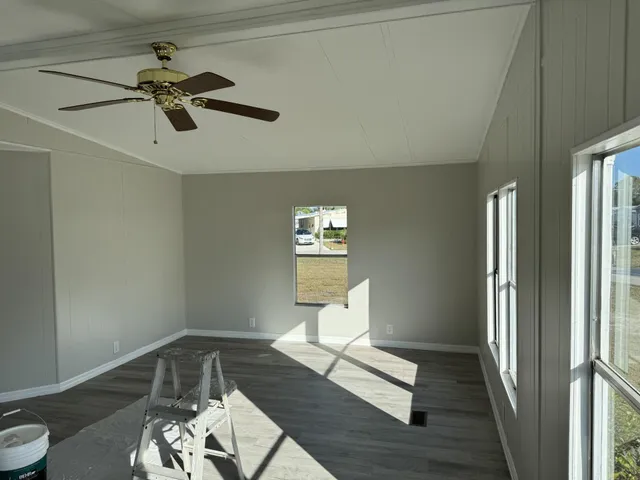 a living room with wooden floor and a ceiling fan