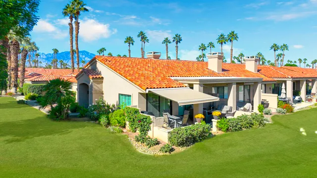 a view of a patio with dining table and chairs with a floor to ceiling window and potted plants