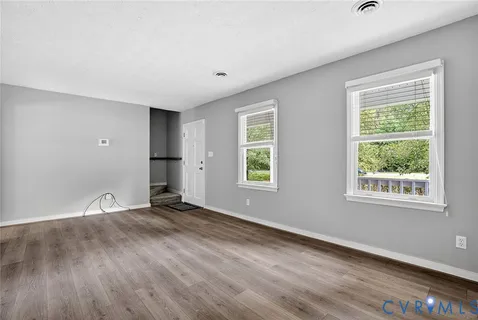 an empty room with wooden floor and windows