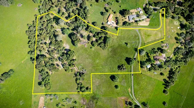 an aerial view of a residential houses with outdoor space and trees