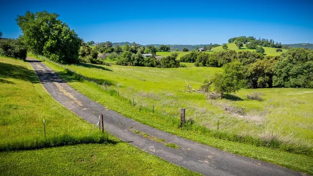 an aerial view of a residential houses with outdoor space and trees